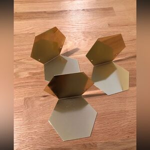 3 gold metallic floating shelves for books.